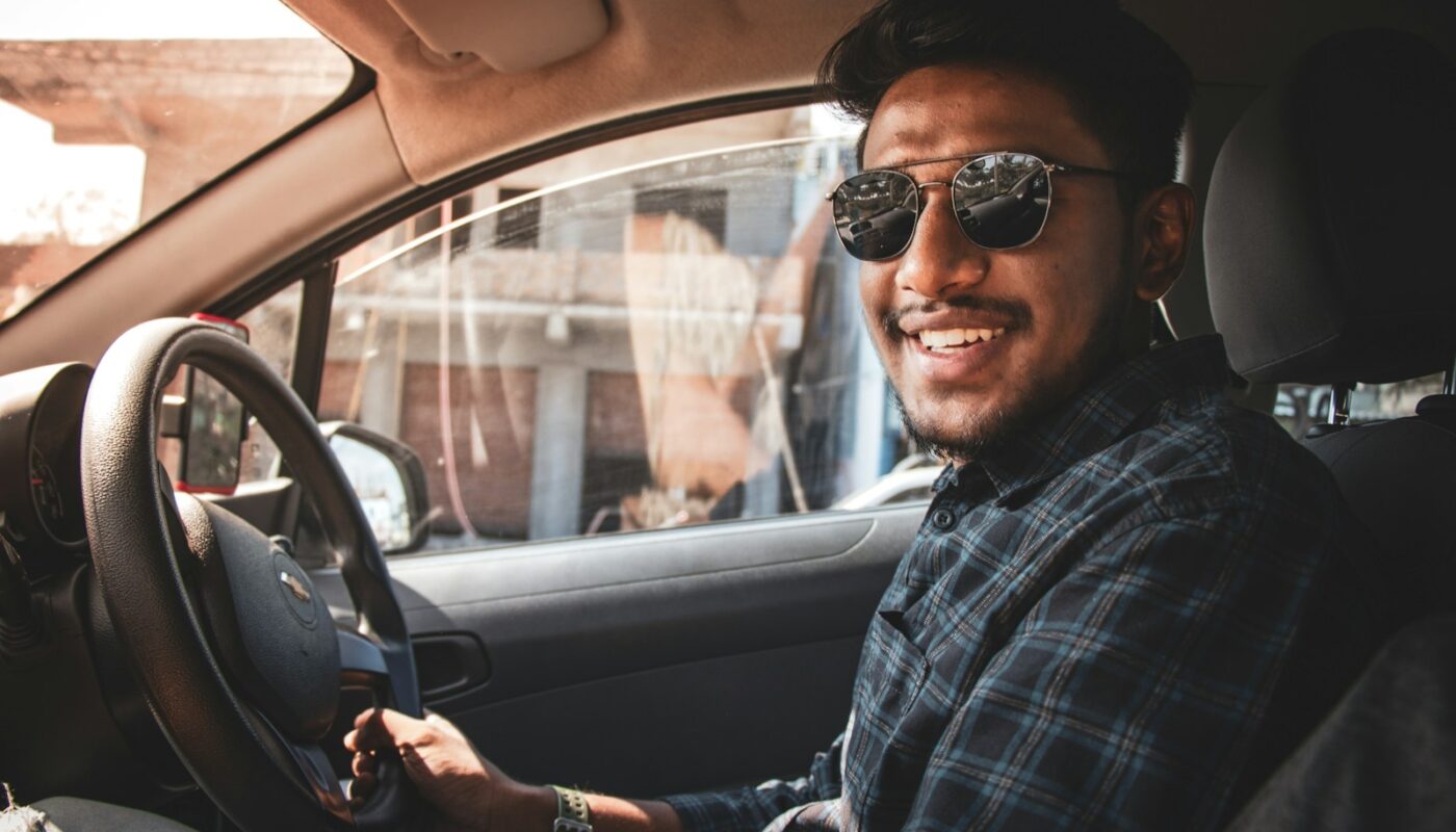 man in black and white plaid dress shirt wearing black sunglasses driving car