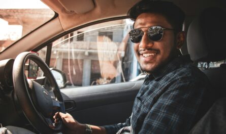 man in black and white plaid dress shirt wearing black sunglasses driving car
